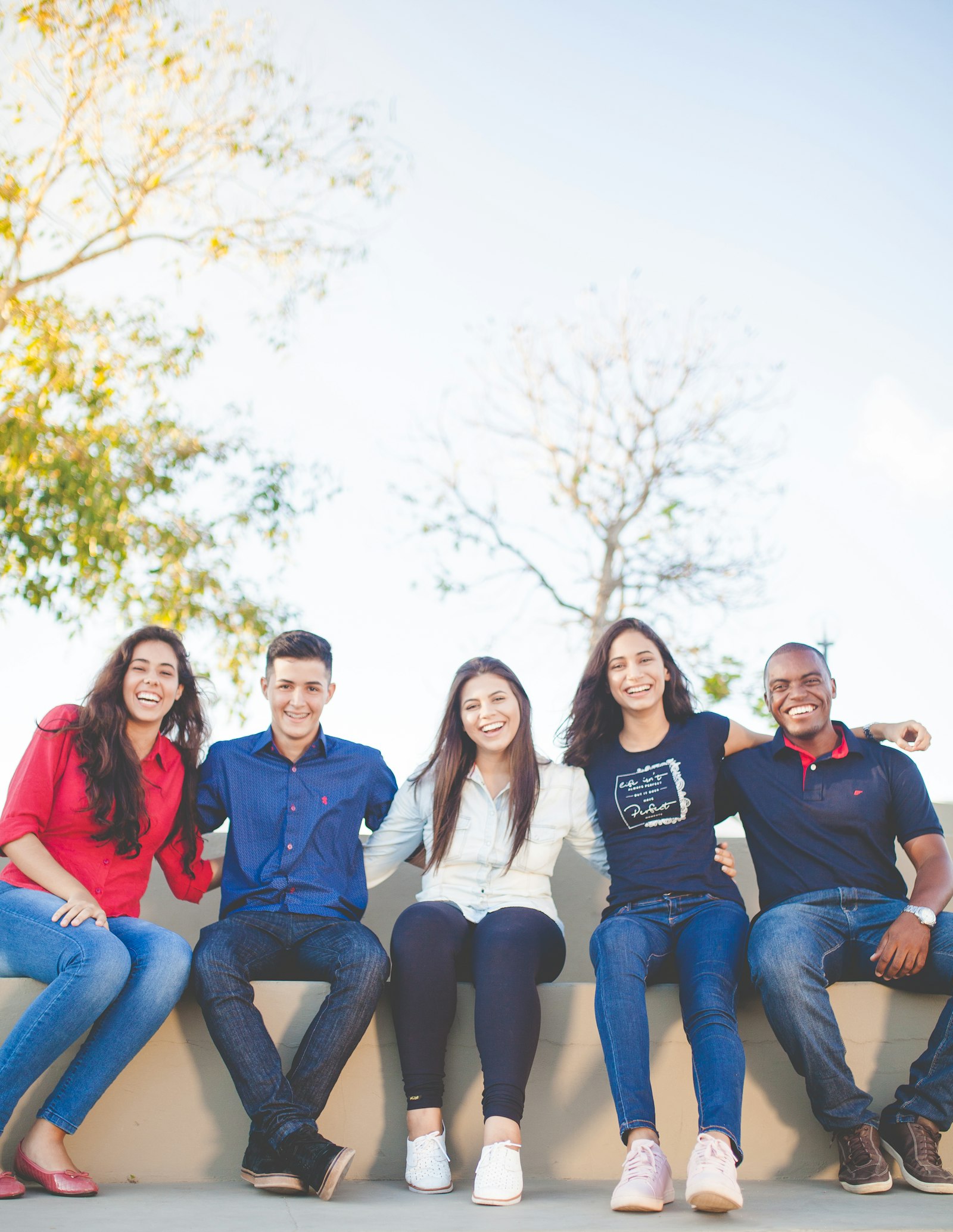 A joyful group of young people sitting together outdoors, laughing